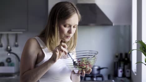 Beautiful-pregnant-woman-eating-salad-and-rubbing-belly